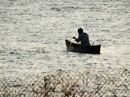 Fisherman retrieving his net at sunsetの写真素材