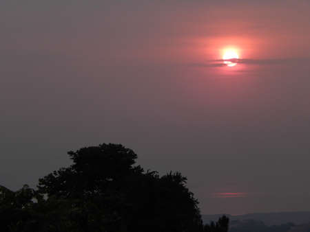 Glowing red sunset in a smoky hazy skyの写真素材