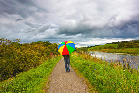 A man walking in the rain along Forth and Clyde Canal, Scotlandの写真素材