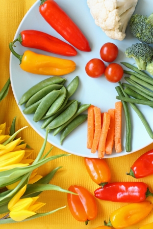 Fresh vegetables on colourful table with yellow tulipsの写真素材