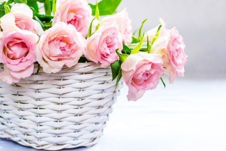 Beautiful, pink roses in a white basket close upの写真素材