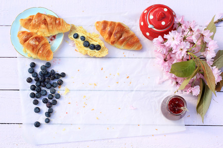 Delicious breakfast with fresh croissants and Japanese cherry flowers in the garden,Layout with free text spaceの写真素材
