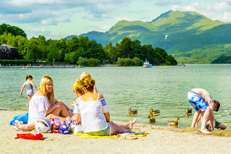Mothers with children on the beach on the Summer day at Loch Lomond, Luss, Scotland, UKのeditorial素材