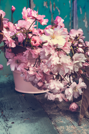 Romantic Spring background with a vase of Japanese cherry blossoms on wooden tableの写真素材
