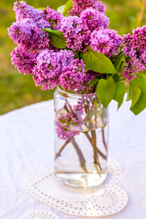 Romantic, beautiful lilac flowers in the glass vase outside, on the garden table.の写真素材