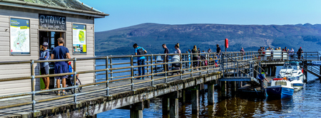 Tourists on the pier in Luss at Loch Lomond, Scotland, 25 August 2019. People relaxing and having fun during one of the hot days in Summer.のeditorial素材