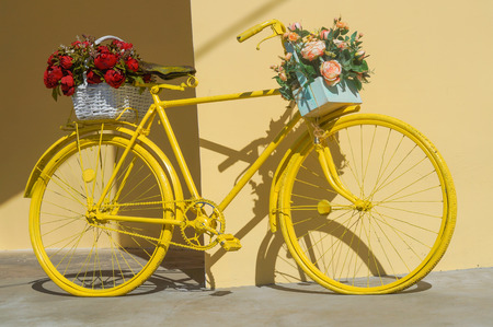 Colorful painted yellow bicycle decorated with flowersの写真素材