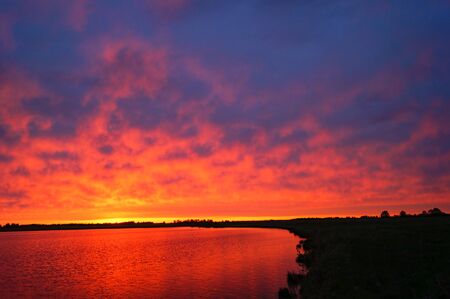 Beautiful red and pink sunset over the lake in summer eveningの写真素材