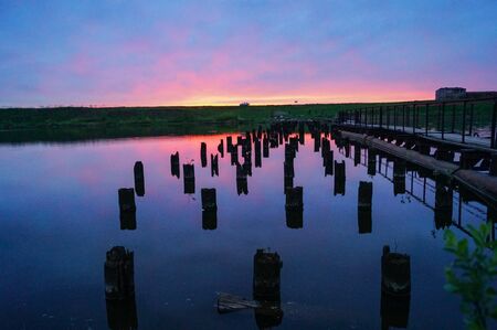 Beautiful violet-blue sunset on a small river wooden posts in the water bridgeの写真素材
