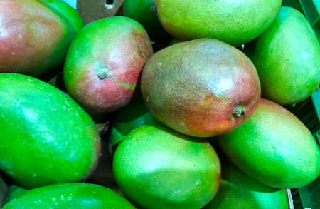 many red green mangoes close-up peeled background in a shopの写真素材