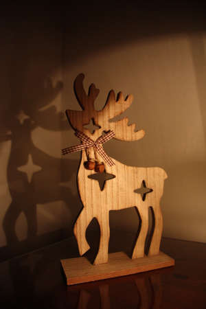 Wooden deer christmas toy on table with light of lamp and shadow on the wallの写真素材