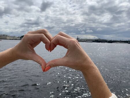 Heart from hands on city and river backgroundの写真素材