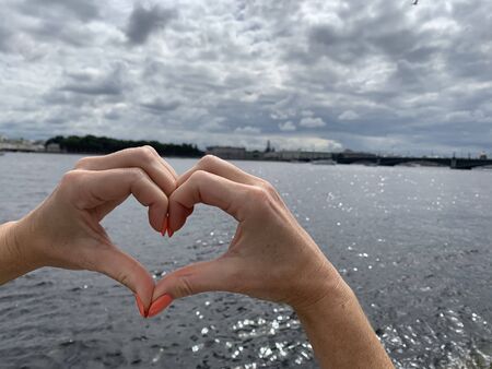 Heart from hands on city and river backgroundの写真素材