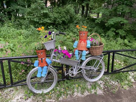 Street installation. Bicycle with flowers basket and pots characters near the black fenceの写真素材