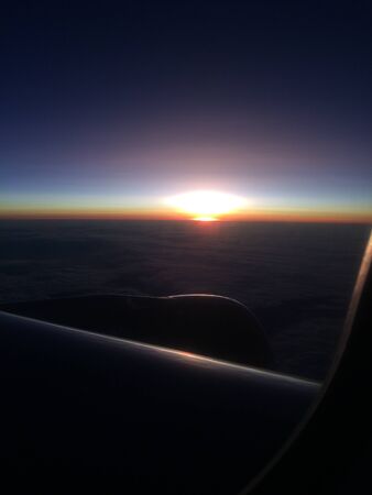 Beautiful sunset or sunrise sky above clouds with dramatic light. Cabin view from airplaneの写真素材