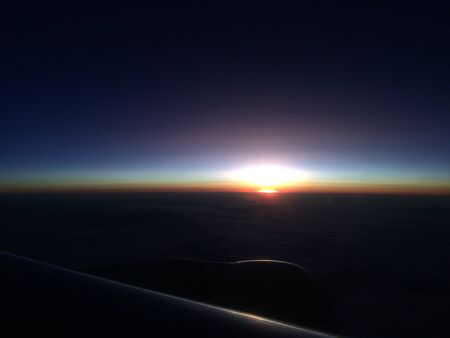 Beautiful sunset or sunrise sky above clouds with dramatic light. Cabin view from airplaneの写真素材