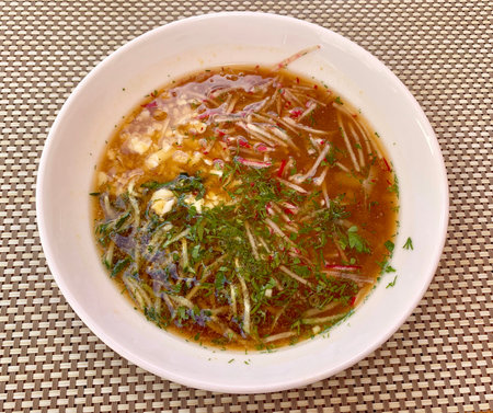 Traditional Russian summer cold soup okroshka with kvass in bowl on wooden background. Top view.
