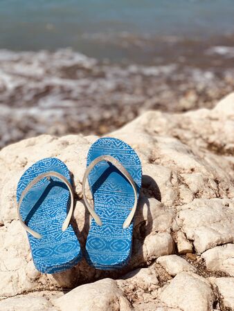 Stylish flip flops on the stone near sea, space for text. Beach accessoriesの写真素材