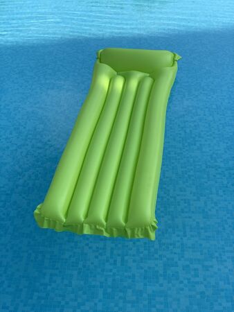 green inflatable mattress floating on water surfaceの写真素材