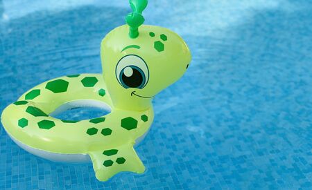 floating ring childish toy on blue water swimpool with waves reflecting in the summer sunの写真素材