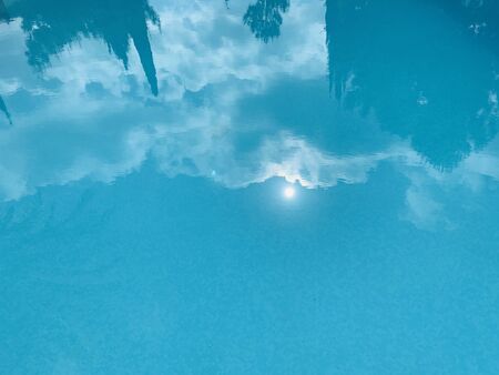 Swimming pool with cloud's reflections sun houses treesの写真素材