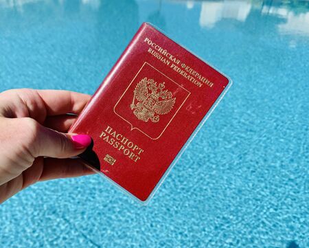International Russian passport in a male hand against a swimming pool backgroundの写真素材