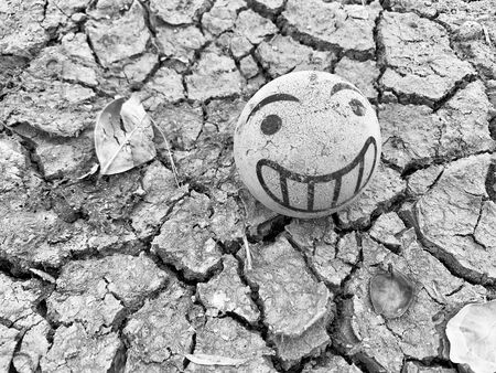 Top view shot of cracked dry soil with smiling ball and leaf. depressive moodの写真素材