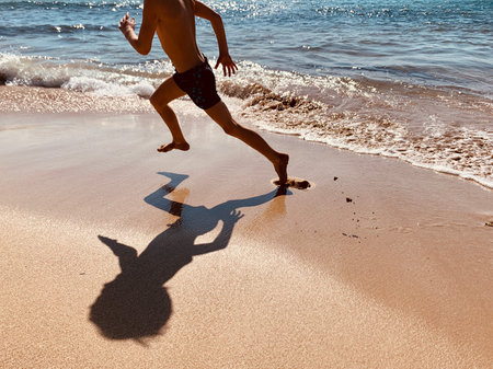 young boy running on the beach in summerの写真素材