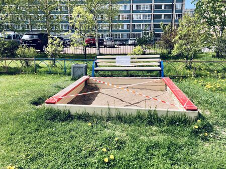Warning tape on the sandbox at a playground to prevent kids from playing in it during coronavirus outbreakの写真素材
