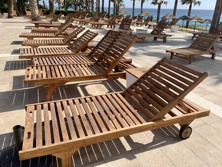 modern wooden sunbeds by turquoise swimming pool.の写真素材