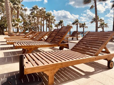 modern wooden sunbeds by turquoise swimming pool.の写真素材