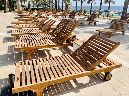 modern wooden sunbeds by turquoise swimming pool.の写真素材