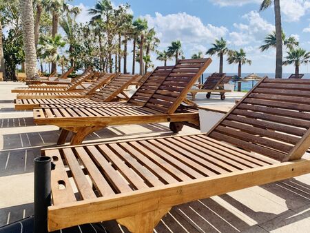 modern wooden sunbeds by turquoise swimming pool.の写真素材