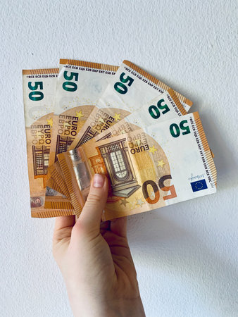 50 euros in female hand isolated on white background.