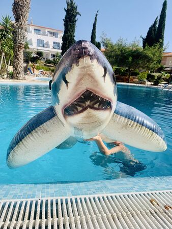 pool toy shark inflatable in swimming pool in hand with boyの写真素材
