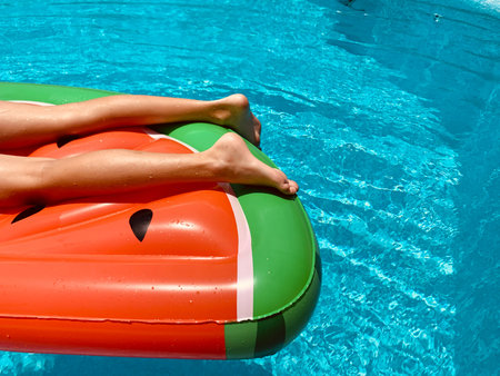 Teenaged boy floating in a swimming pool in an inflatable watermelon