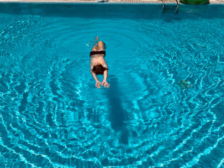 Teenage boy swimming in blue water of swimming pool.の写真素材