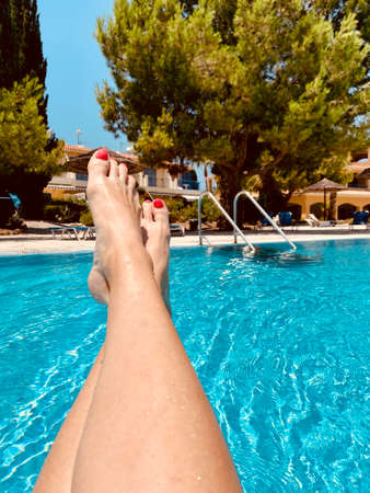 cropped shot of woman sitting in inflatable ring at pool side of hotel female legsの写真素材