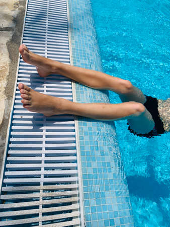 Teenage boy swimming and relax in the swimming pool on vacation in summer seasonの写真素材