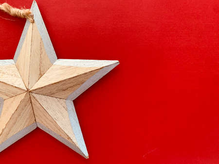 Background with wooden Christmas decoration star on red background. Space for text.の写真素材