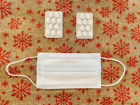 medical mask, pills on a red christmas background. Medicine new year 2021. face fom tablets and maskの写真素材
