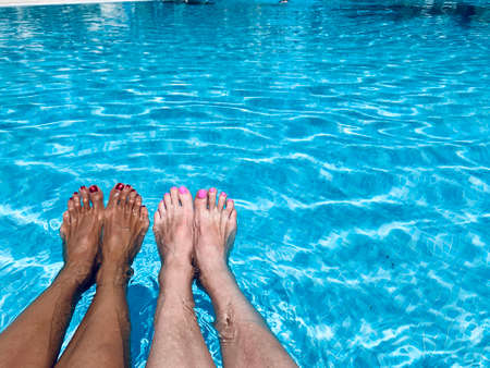 Couple of women sunbathing at the swimming pool female legsの写真素材