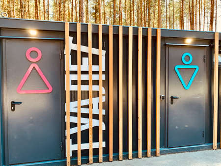 Modern russian street toilet in park in summer day. Writing on the cabin femail and male tualet means Toilet wc sign on the doorの写真素材