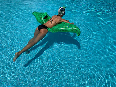 Relax in luxury swimming pool. Fashion crocodile leather and girl in water. Summer vacation and travel to ocean, maldives. Adventures of girl on crocodile. woman in water sea with inflatable mattress.の写真素材