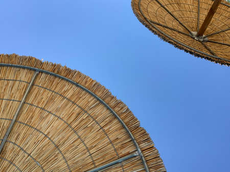 Umbrella beach. Wicker beach umbrella, bottom view. Sunshade beach, closeup blue skyの写真素材