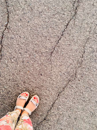 female legs on the asphalt in colorful pants and sandalsの写真素材