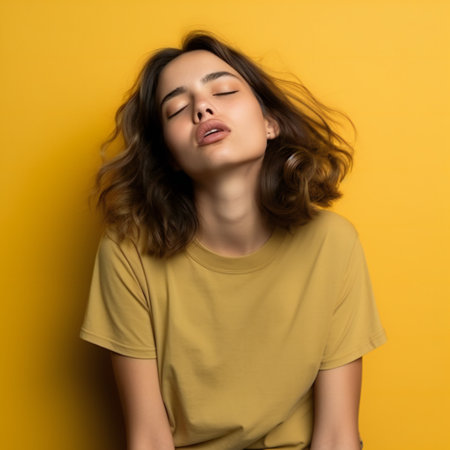 Sleepy girl wearing casual t shirt over yellow background with closed eyes tired .の素材