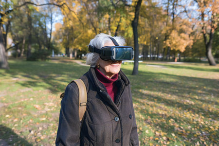 Happy senior woman watching through vr goggles in parkの素材
