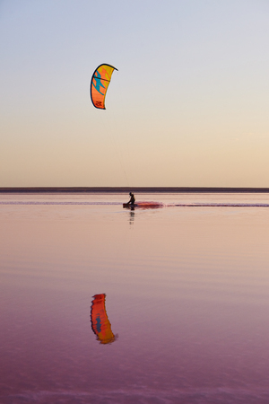 Kitesurfing on pink color lake with reflectionの写真素材