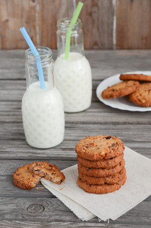 Chocolate and cranberry cookies with milk on the rustic wooden tableの写真素材